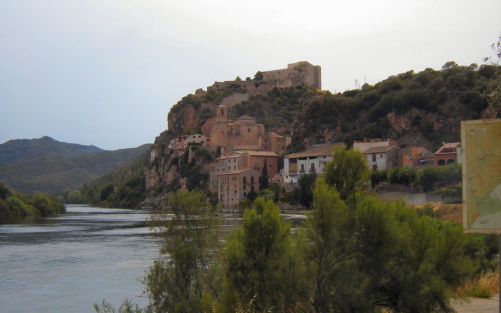 Het oude dorp Miravet met zijn huizen tegen de helling, weerspiegeld in de Ebro