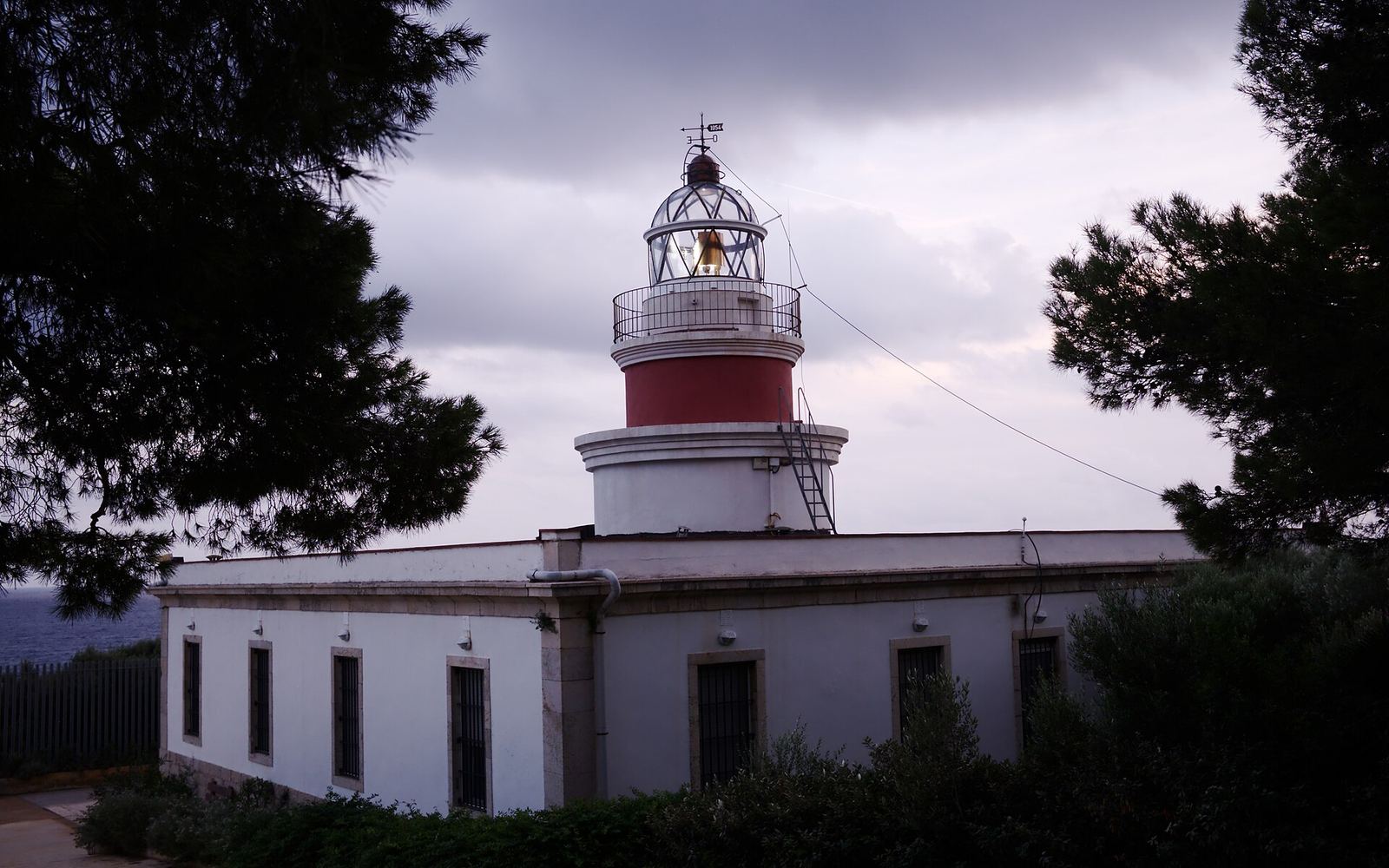 De witte vuurtoren Far de Salou met rode toren boven op de kliffen van Cap Salou